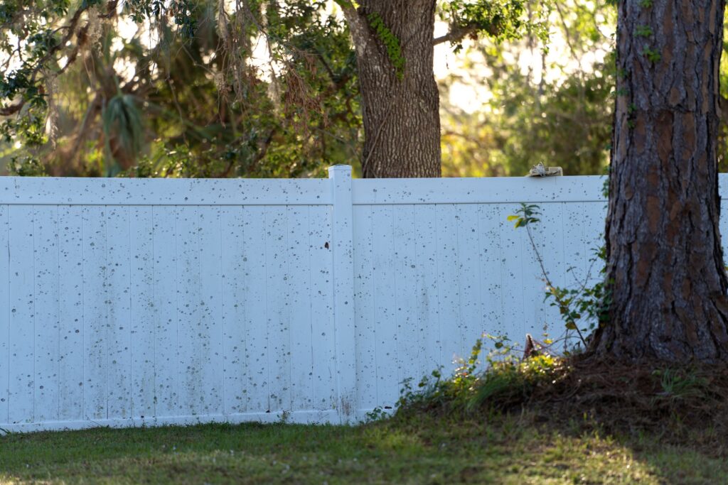 Dirty white vinyl picket fence on green lawn surrounding property grounds for backyard protection and privacy