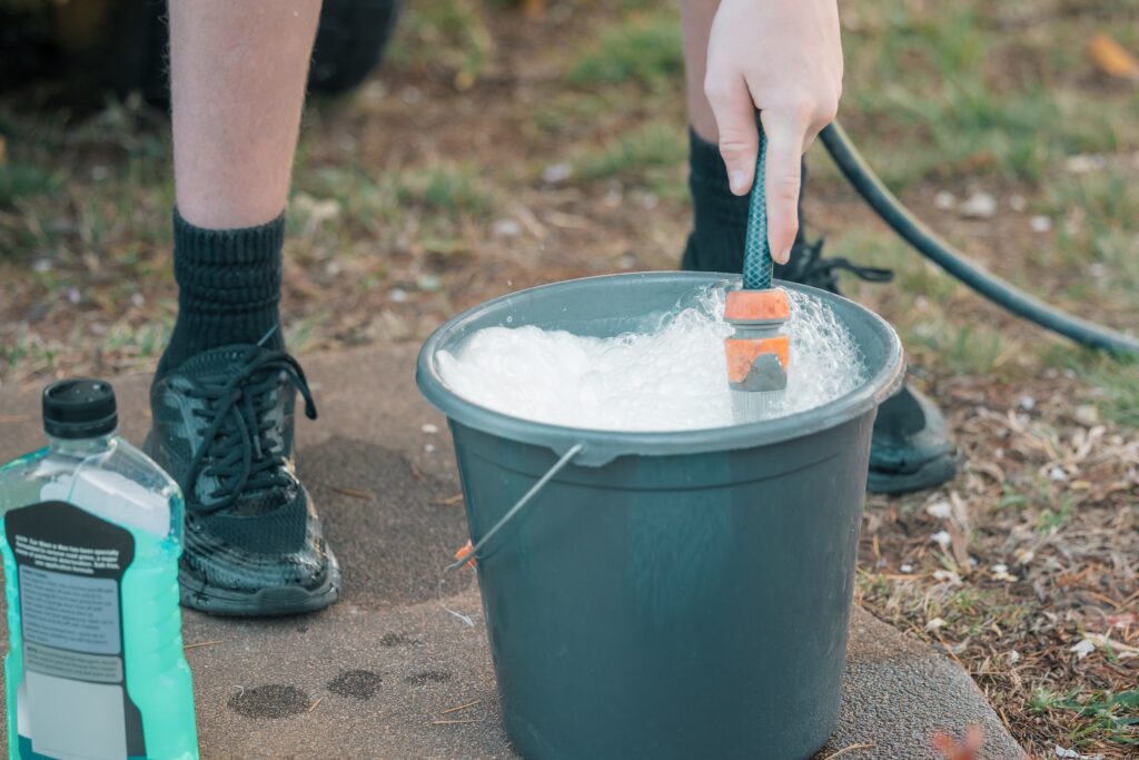 Teenage boy filling bucket with soapy water